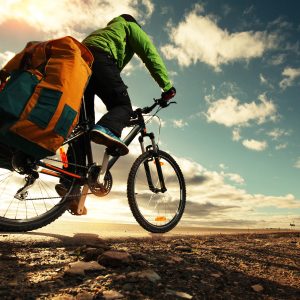 Bicycle tourist with loaded bike riding on an empty road